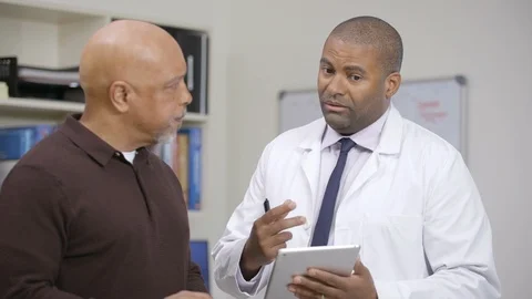 Male doctor reviewing patient info on iPad at nursing station, camera move left Stock Footage