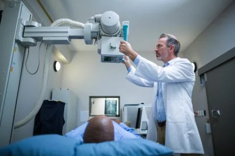 Male doctor sets up the machine to x-ray over patient Stock Photos