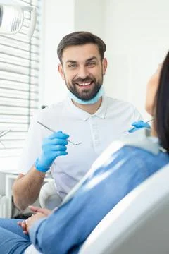 Male doctor smiling at the camera with instruments in the hands with client s Stock Photos