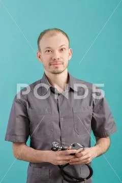Male doctor with stethoscope smiling and looking at camera on blue background Stock Photos