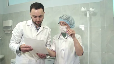 Male doctor talking to nurse holding blood sample Stock Footage