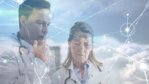 Male doctor tapping network node while female doctor scrolling tablet, reviewing Video stock 312099585