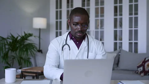 Male doctor using computer and typing while sitting at table in modern office Stock Footage 158519220