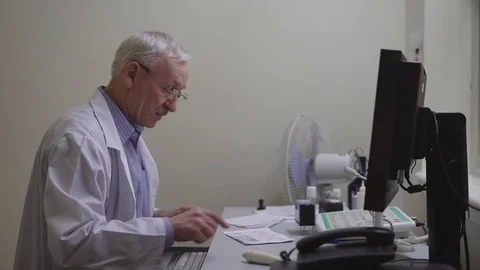 Male doctor using computer. Side view of senior male doctor in uniform sitting Stock Footage 74598583