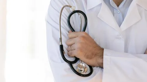 Male doctor in white coat uniform holding stethoscope. Stock Photos