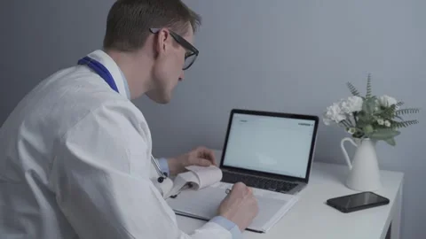 Male doctor working at computer in private medical practice, checking patients Stock Footage 252303124