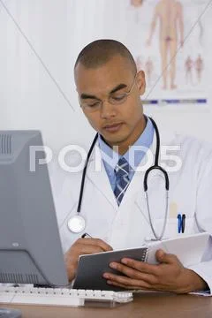 Male Doctor Writing In Notebook