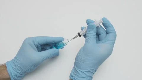 Male doctor's hands in strike gloves collect blue liquid medicine Stock Footage 264092425