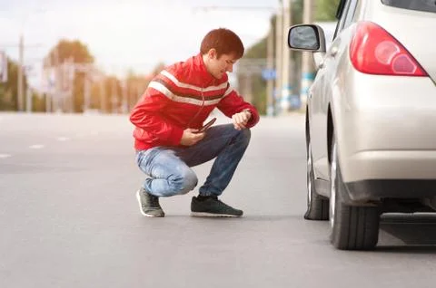 Male driver checking wheel after car breakdown Stock Photos