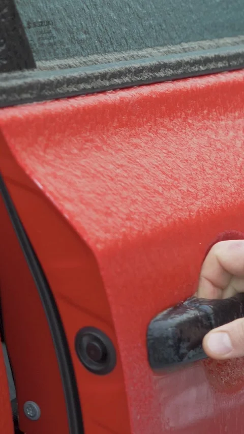 Male driver hand pulls ice covered door handle and opens door of red car Stock Footage 345605292
