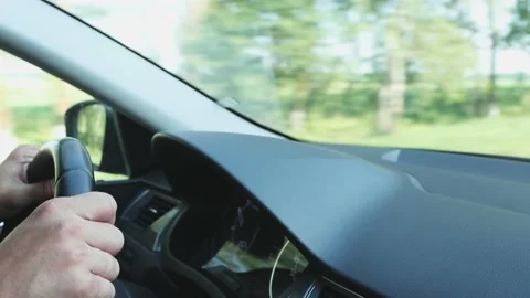 The male driver holds his hands on the steering wheel of the car and drives Stock Footage 157526257