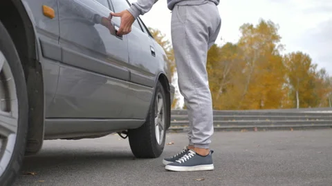 A male driver opens the driver's seat door, gets behind the wheel of a car and Stock Footage 164805929