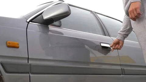 The male driver opens the driver's seat door with a key, gets behind the wheel Stock Footage 164852710