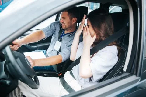 Male driving instructor trying to avoid a collision with another car. Scared Stock Photos