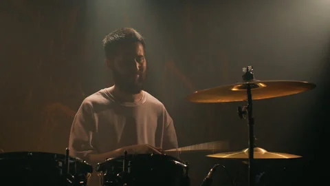 Male drummer plays a drum kit in a dark music studio. The rock band is Stock Footage 260577301