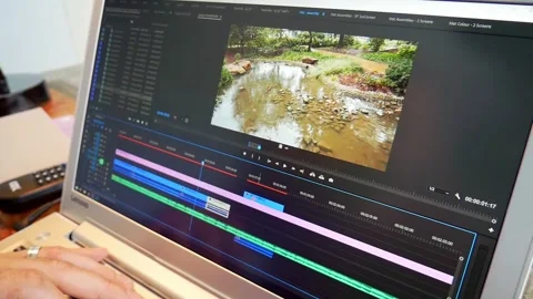Male editing video content inside Adobe Premiere Pro on a laptop Stock Footage 320516451