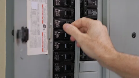 Male electrician resetting tripped circuit breaker for electrical outlet. Stock Footage