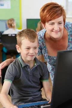 Male elementary pupil in computer class with teacher Foto stock