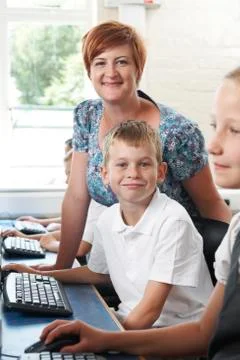 Male elementary pupil in computer class with teacher Stock Photos