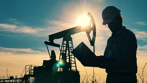 Male engineer and a functioning pumpjack in sunlight. Oil and gas industry Video stock 142429171