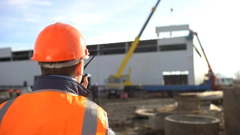 Male engineer, builder, foreman, worker in orange a uniform and hard hat using a Stock Footage 98321304