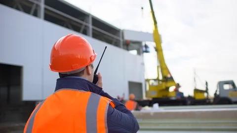 Male engineer, builder, foreman, worker in orange a uniform and hard hat using a Stock Footage 98322510