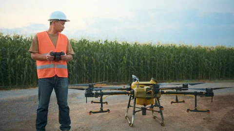 Male engineer controlling drone spraying fertilizer and pesticide over farmla Stock Footage 170508707