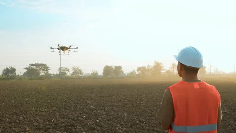Male engineer controlling drone spraying fertilizer and pesticide over farmla Video stock 170511071