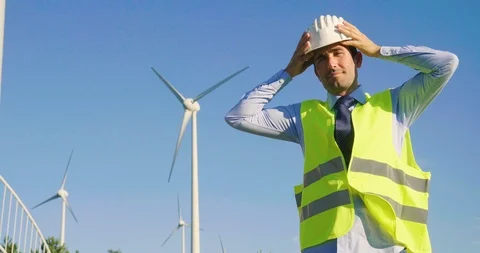 A male engineer is controlling a functioning of wind turbines in a wind farm. Stock Footage 115124876