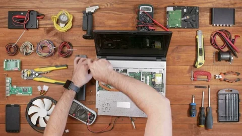 Male engineer disassembles a laptop with a screwdriver. Wooden table top view Stock Footage 72419397
