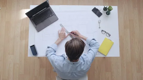 Male engineer drawing draft, looking at laptop screen, construction project Stock Footage 166047719