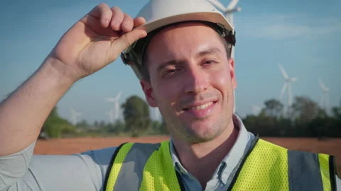 Male engineer looking to camera with wind turbine farm background. Stock Footage 229112471