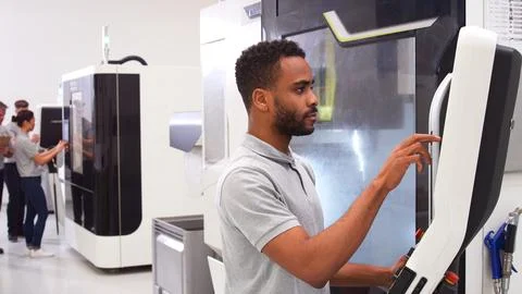 Male Engineer Or Apprentice Using CNC Machine In Factory Foto stock