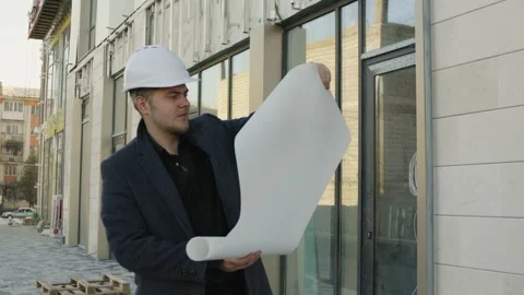 Male engineer or architect checking a building plan on a construction site Stock Footage 323165959