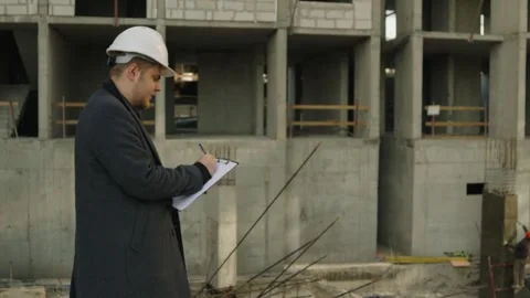 Male engineer or architect checking plans on a construction site Stock Footage 323166700