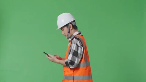 Male Engineer With Safety Helmet Using Smartphone While Walking Green Screen Video stock 247997018