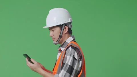 Male Engineer With Safety Helmet Using Smartphone While Walking On Green Screen Stock Footage 247999033