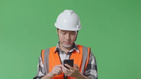 Male Engineer With Safety Helmet Using Smartphone While Walking On Green Screen Stock Footage 248000383