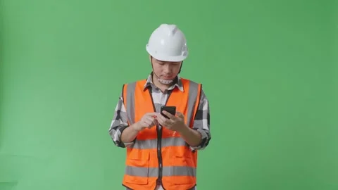 Male Engineer With Safety Helmet Using Smartphone While Walking On Green Screen Stock Footage 248001419