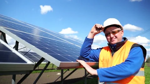 Male engineer stands against the background of solar panels lifting helmet Stock Footage 168178536