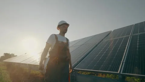 A male engineer with technical documentation walks between solar panels Stock Footage 263753263