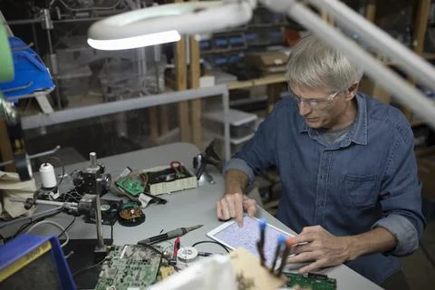 Male engineer using digital tablet at workbench in workshop Stock Photos