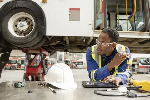 Male engineer using digital tablet in bus maintenance facility Stock Photos