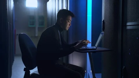 Male engineer using laptop and working on IT project at table in data center Stock Footage 162733311