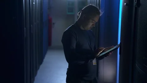 Male engineer using tablet and working with hardware while standing in data Stock Footage 162224223