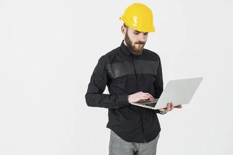Male engineer wearing hardhat using laptop against white background Stock Photos