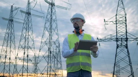 Male engineer is working on a tablet computer while being near power lines Stock Footage 101200294