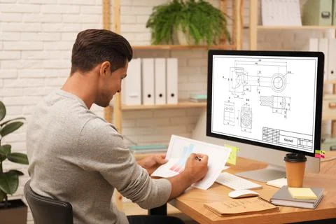Male engineer working with technical drawing on computer in office Foto stock