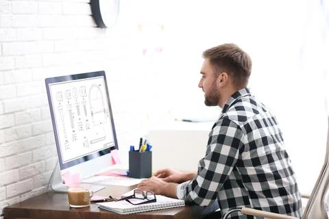 Male engineer working with technical drawing on computer indoors Foto stock
