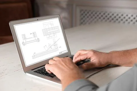 Male engineer working with technical drawing on laptop indoors, closeup Foto stock